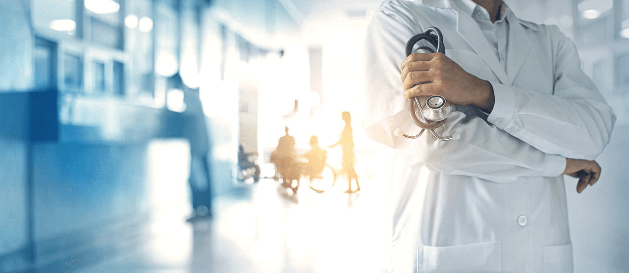 Doctor with stethoscope in hospital hallway.