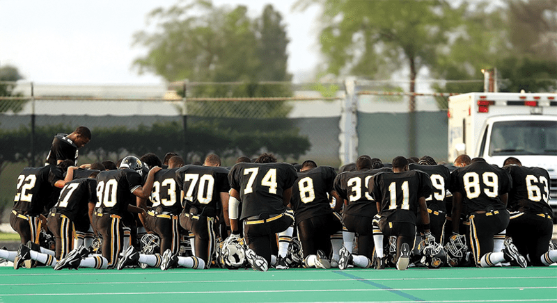Football team kneeling on the field together
